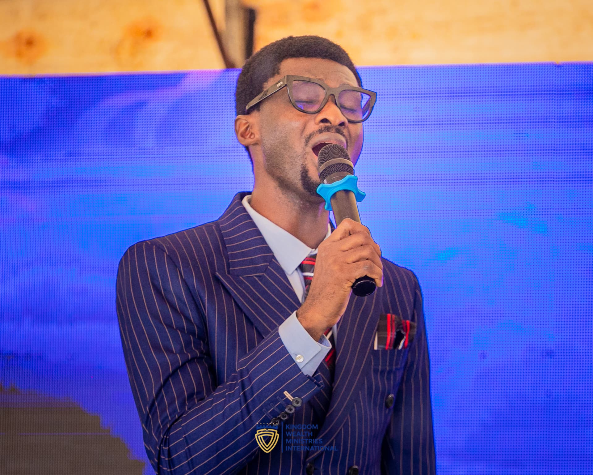A KWMI minister leading worship with a microphone