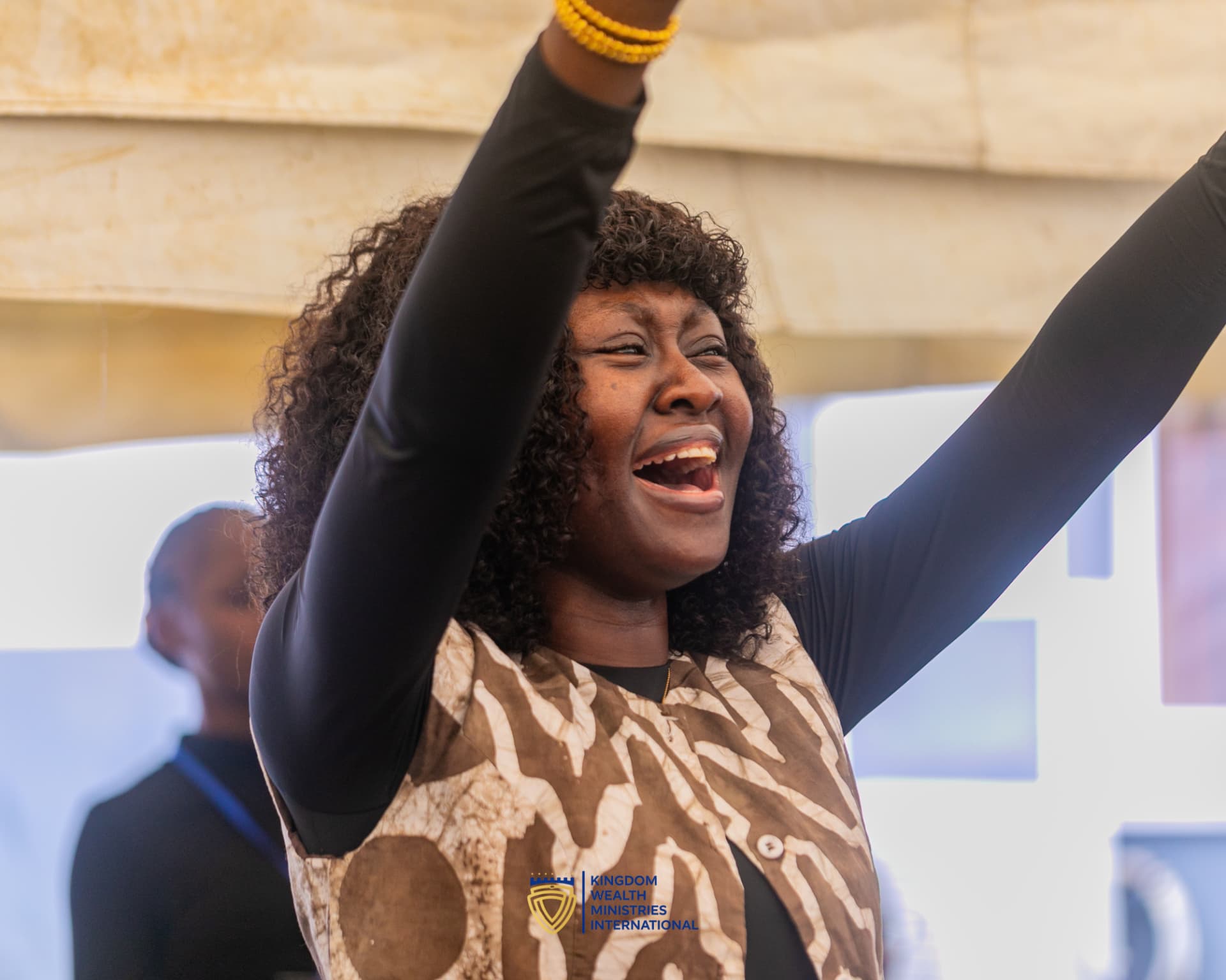 A worshipper with hands raised in praise at a KWMI gathering
